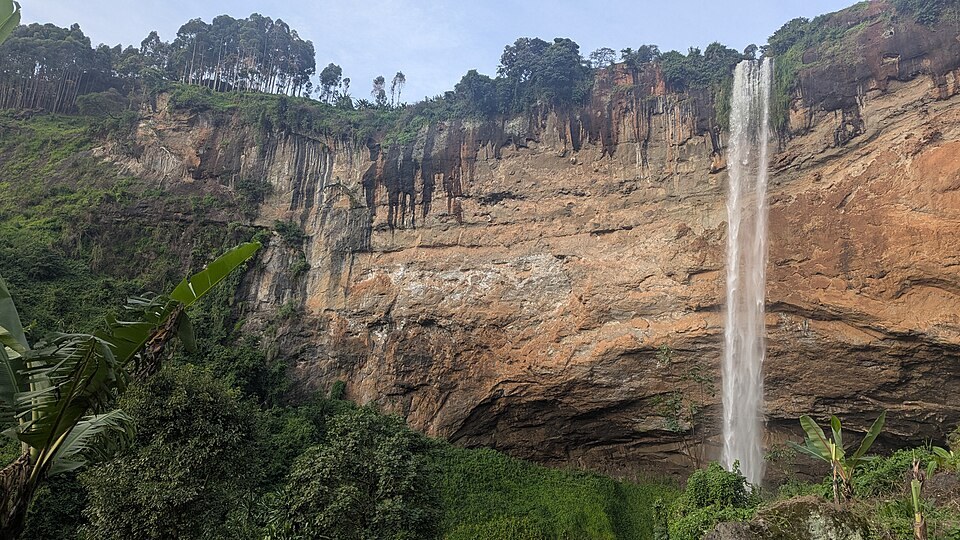 A waterfall descending beside the cliffs at Sipi Falls.